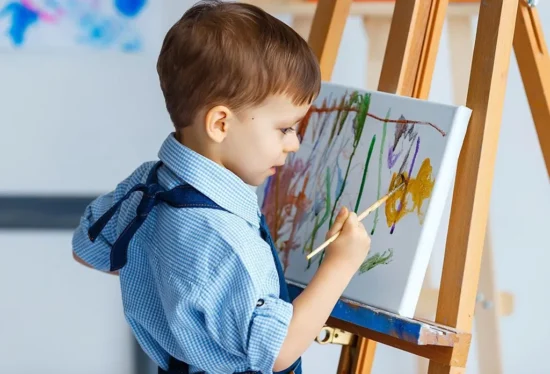 A toddler painting on a canvas