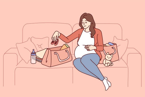 Pregnant woman is packing things for unborn child in bag going to maternity hospital before giving birth. Pregnant girl is sitting on couch getting ready for motherhood and raising baby